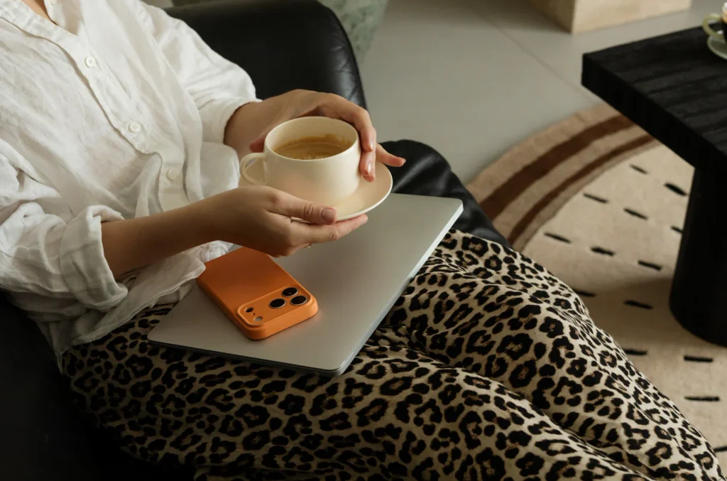 A lady is holding a cup of coffee and thinking about hiring a designer for her project